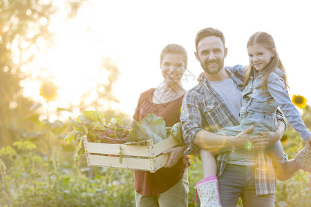 农场里带蔬菜的微笑家庭的肖像图片