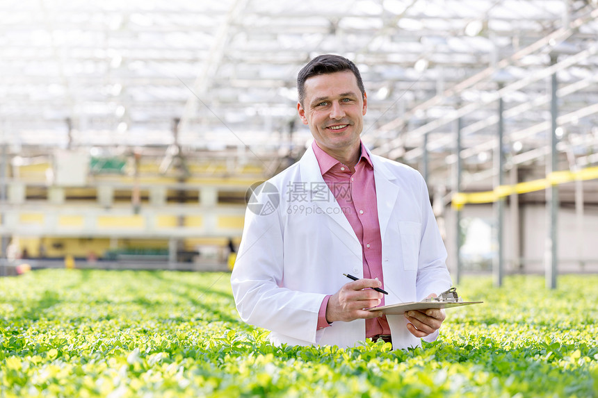 微笑科学家的肖像,站剪贴板中的草药温室图片