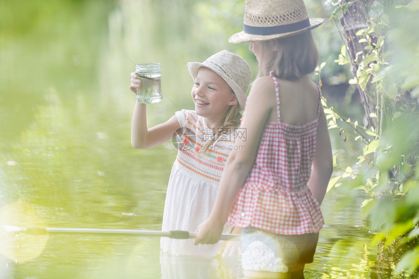 微笑的女孩站湖里看着罐子图片