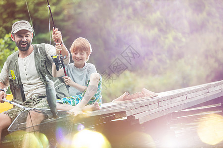 快乐的父子湖岸的蝴蝶渔网里钓鱼的倾斜镜头图片