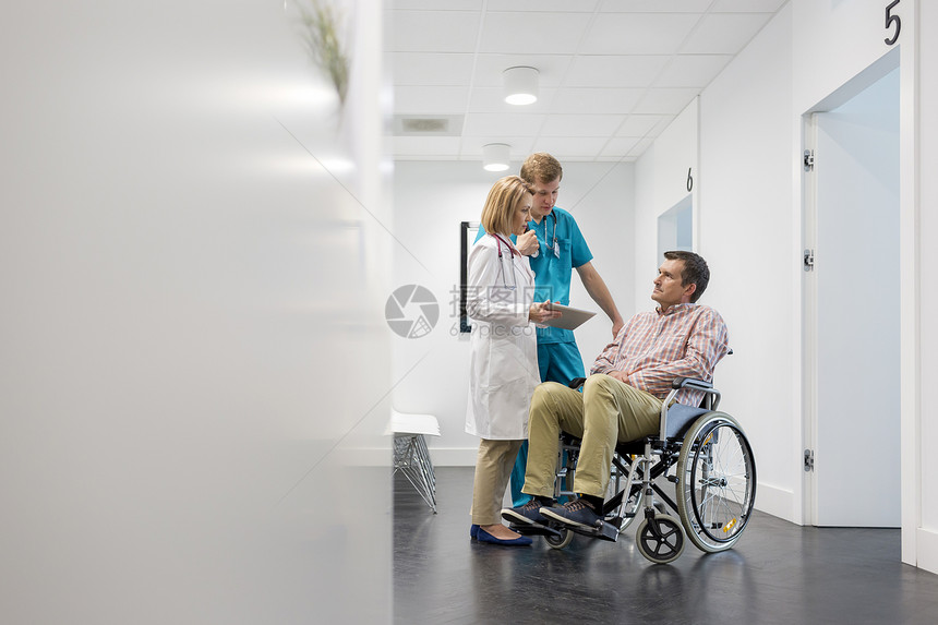 成熟的医生与数字平板电脑解释病人轮椅上的医院图片
