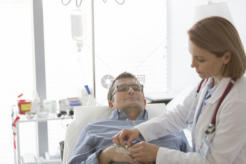 医生调整生理盐水静脉滴注给住院的成熟患者图片
