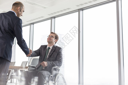 办公室开会期间,商人会议室与微笑的残疾同事握手图片