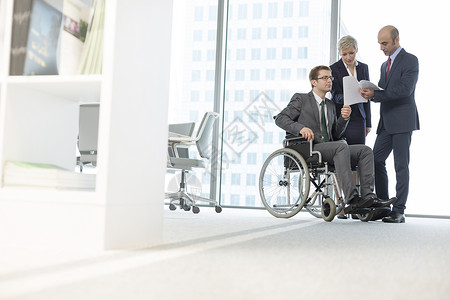残疾商人与办公室会议室的同事讨论文件图片