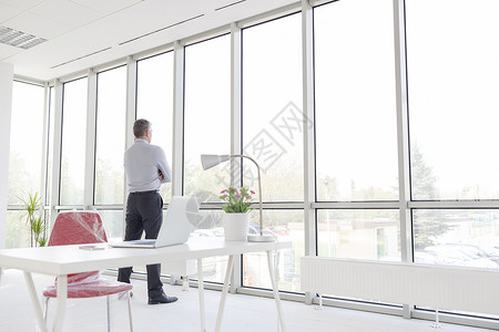 整整段深思熟虑的成熟商人透过窗户看着新的办公室图片