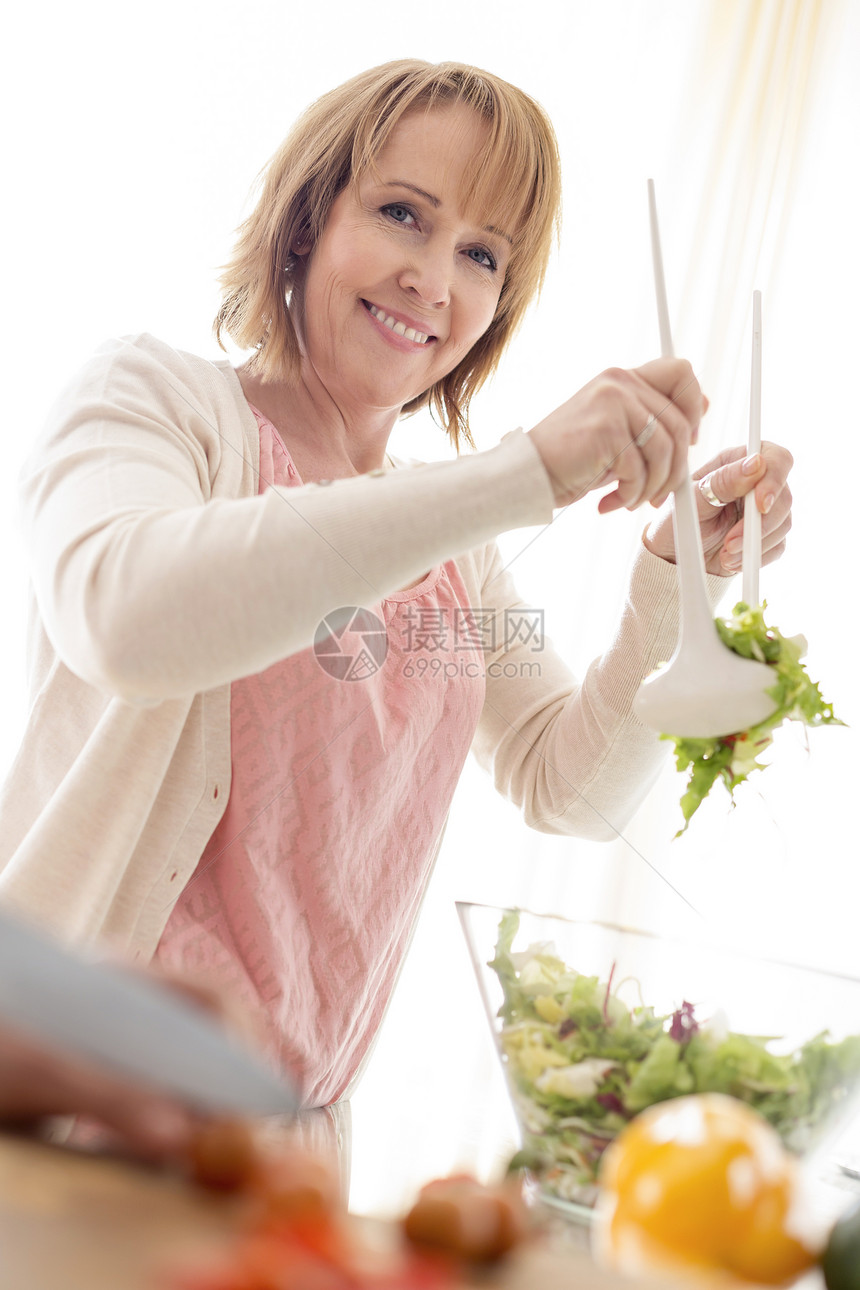 微笑的女人厨房准备沙拉碗的肖像图片