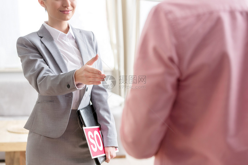 年轻的女售货员着标语牌文件,公寓里问候男人图片