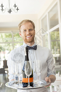 自信的年轻侍者餐厅端酒的肖像背景图片