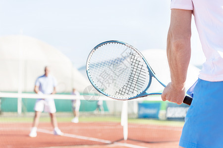 满立减活动成年男子网球场上与朋友起玩球拍的中段背景