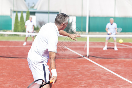 男子夏季周末红场打网球双打时摆动球拍图片