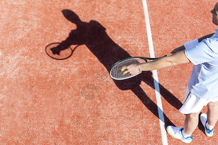 成熟男子红场发球网球的高角度视角图片