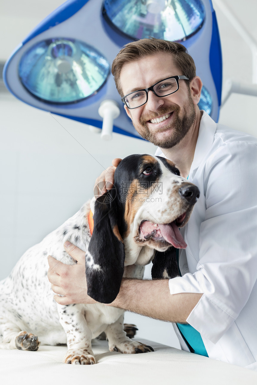 兽医诊所床上带狗微笑医生的肖像图片