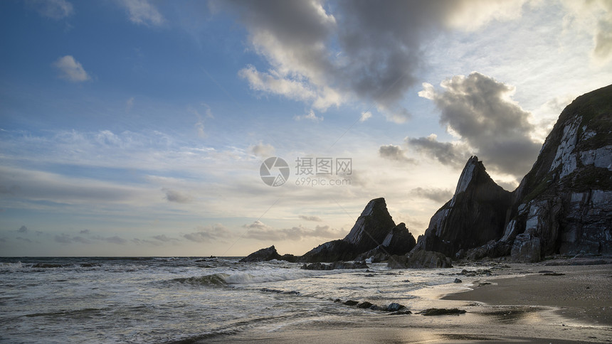 美丽的日落景观图像韦斯特康贝海滩德文英格兰与锯齿状的岩石海滩惊人的云图片