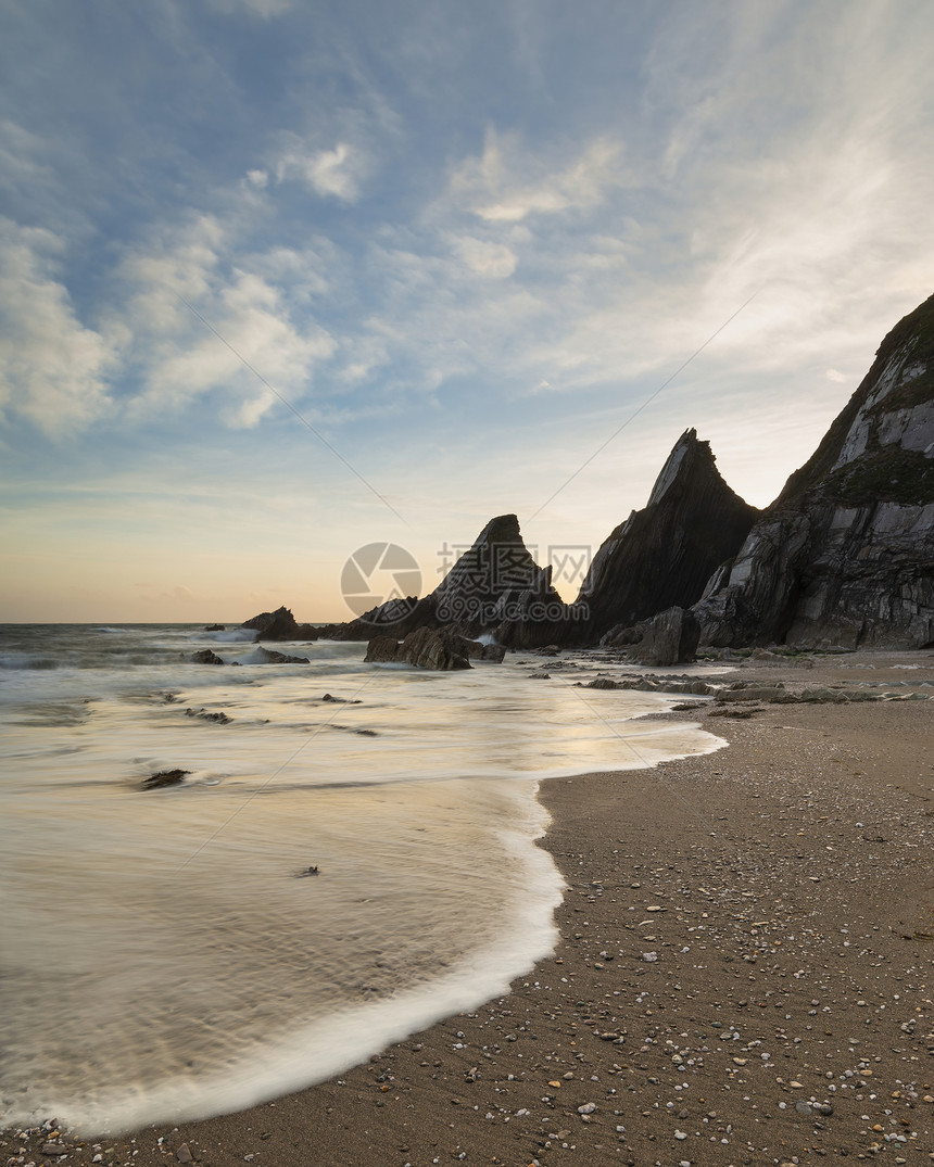 美丽的日落景观图像韦斯特康贝海滩德文英格兰与锯齿状的岩石海滩惊人的云图片