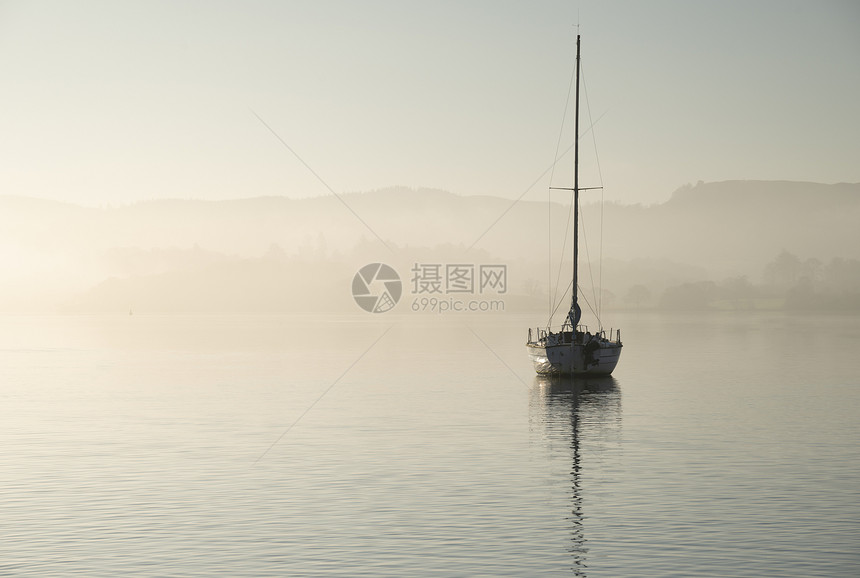 美丽的拔掉插头的景观形象,帆船坐平静的湖水中,宁静的雾蒙蒙的秋日日出图片