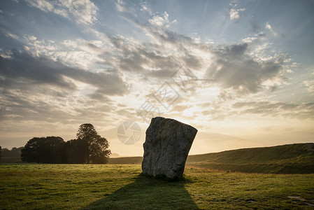 埃夫伯里美丽的夏季日出景观,新石器时代站立的石头英国农村与华丽的光与背景雾背景