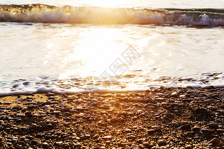 日落时美丽的海浪鹅卵石惊人的假期旅行背景图片