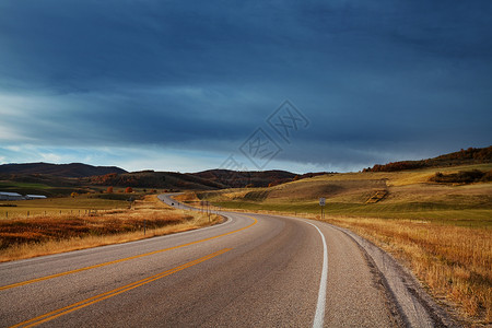 令人愉快的乡村阳光明媚的早晨,乡间道路上五彩缤纷的秋天景象背景