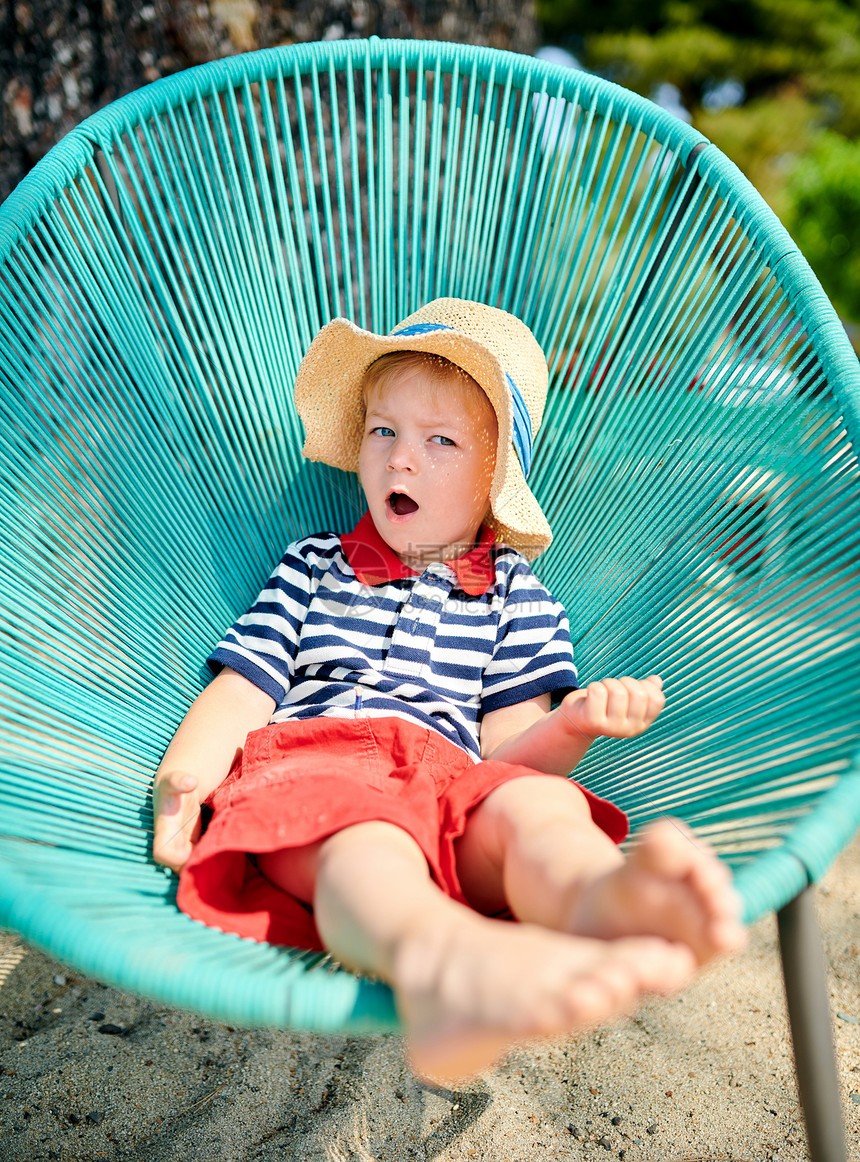两岁的蹒跚学步的男孩坐海滩椅子上图片