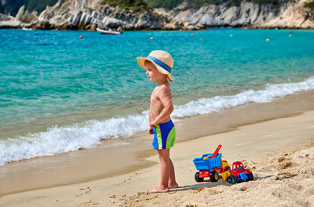 两岁的蹒跚学步的男孩海滩上带着玩具戴着草帽的孩子暑假家庭假期希腊西索尼亚背景