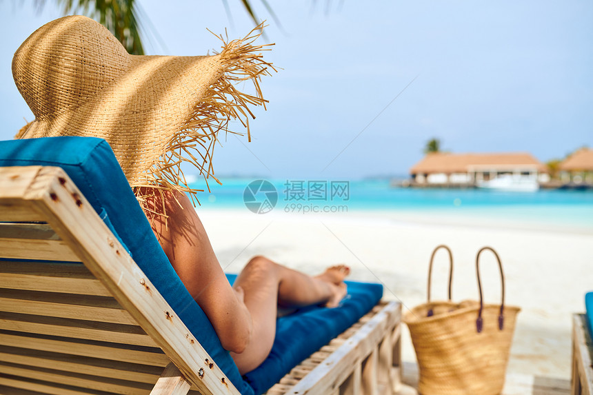 轻的女人海滩上的木制日光浴床上马尔代夫的暑假图片