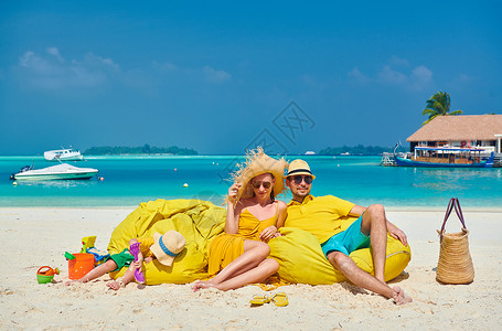 热带短裤海滩上的家人,穿着黄色衣服的轻夫妇三岁的男孩马尔代夫的暑假背景