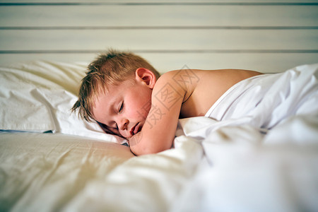 三岁的蹒跚学步的男孩睡毯子下的枕头上图片