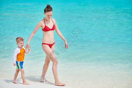 三岁的蹒跚学步的男孩妈妈海滩上散步马尔代夫的暑假家庭假期图片