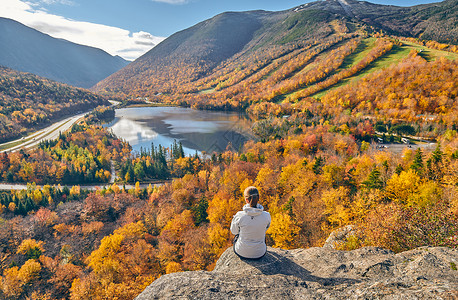 女子徒步旅行艺术家的虚张声势秋天回声湖的景色法国公园的秋天颜色美国新罕布什尔州白山森林背景图片