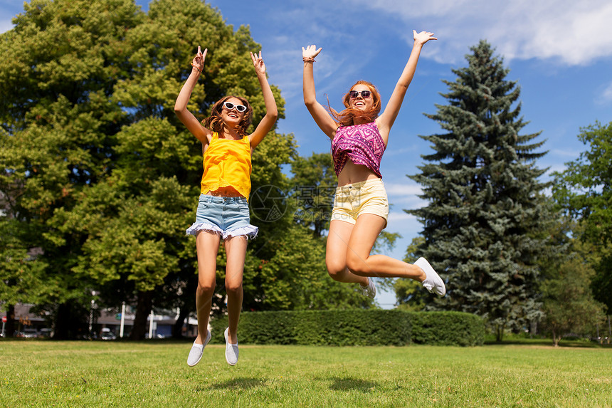 休闲,人与友谊的快乐的十几岁的女孩朋友夏季公园跳跃玩得开心快乐的十几岁的女孩夏天的公园跳图片