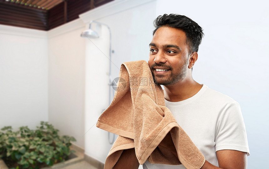 梳洗,卫生人的微笑的印度男子,浴巾干燥他的脸淋浴背景微笑的印度男人带着浴巾冲过淋浴图片