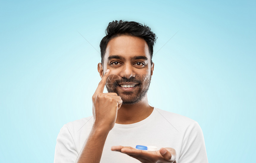 视觉,视力,眼科人的微笑的轻印度男子应用隐形眼镜蓝色背景轻的印度男子戴隐形眼镜图片