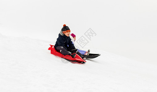 骑着摩托男孩童,雪橇季节快乐的孩子们冬天乘雪橇滑下雪山快乐的孩子们冬天乘雪橇下山背景