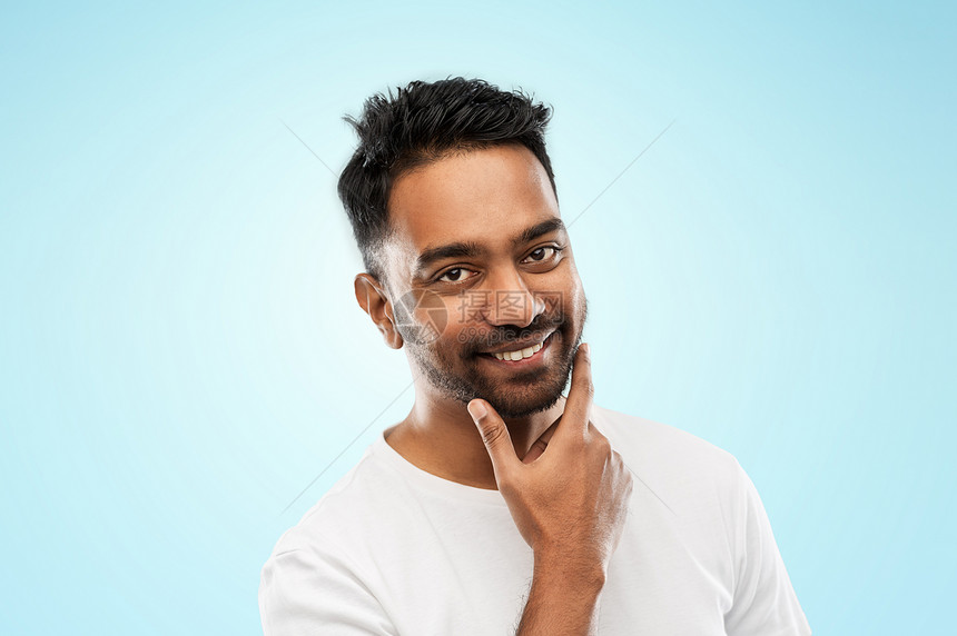 修饰人们的微笑的印度男子触摸他的胡子蓝色的背景微笑的印度男人抚摸他的胡子图片