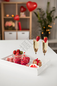 情人节糖果纸杯蛋糕与红色奶油霜心形鸡尾酒棒,香槟杯与草莓,马卡龙,蜡烛礼品盒托盘上情人节的红色糖果背景图片