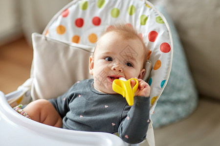 香蕉玩具牙齿童的小女婴牙齿玩具高椅子家里家里的高椅子上放着聚醚玩具的女婴背景