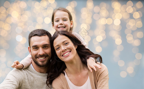 家庭人的快乐的母亲,父亲小女儿节日的灯光背景节日灯光背景下的幸福家庭图片