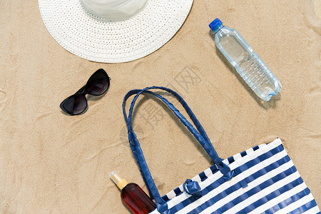 假期,旅行夏季海滩袋,防晒霜,太阳镜帽子沙子上沙滩袋,太阳镜沙滩上的帽子背景