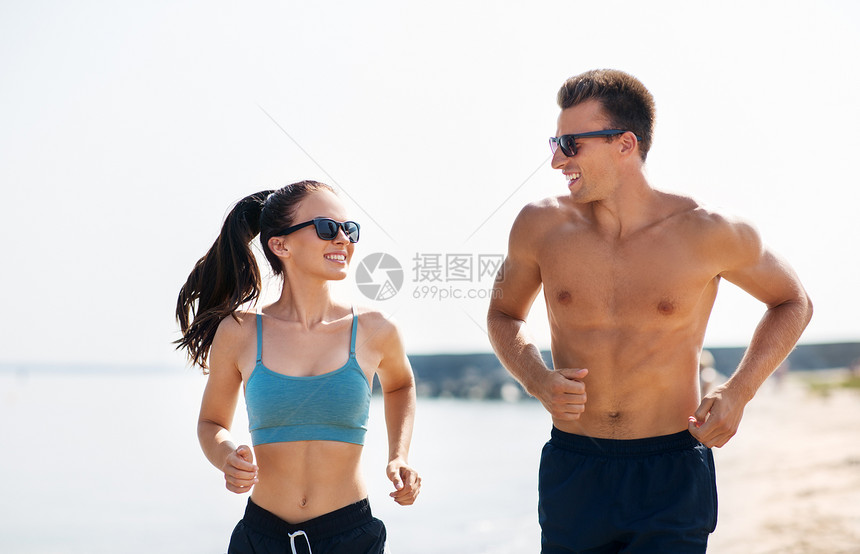 健身,运动生活方式的快乐的夫妇穿着运动服装太阳镜沿着夏季海滩跑步穿着运动服的夫妇海滩上跑步图片