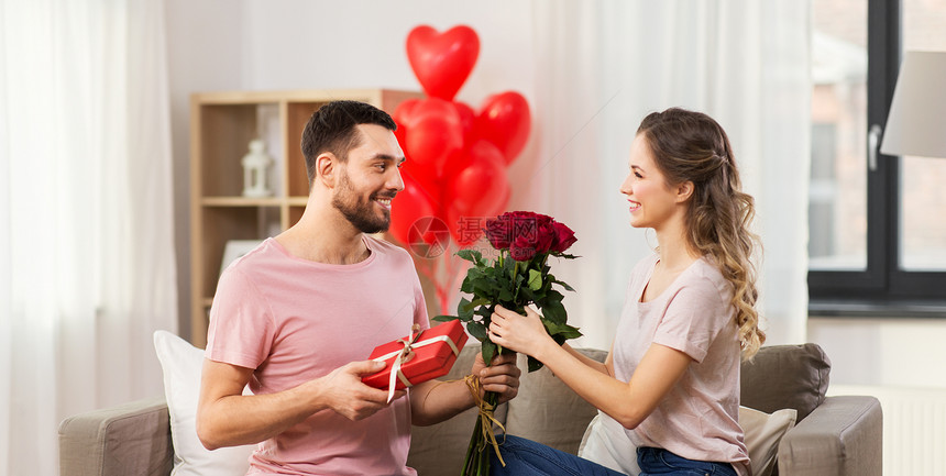 情人节,夫妻,人际关系人的快乐的男人给女人鲜花礼物家里快乐的男人给女人鲜花,并家里礼物图片