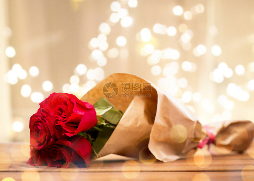 花,情人节假日的红色玫瑰包裹成棕色的纸木制桌子上的节日灯把红玫瑰成纸图片
