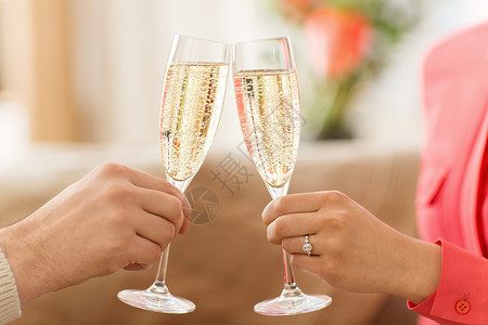情人节,庆祝订婚的夫妇的手叮当香槟杯两个叮当作响的香槟杯背景图片