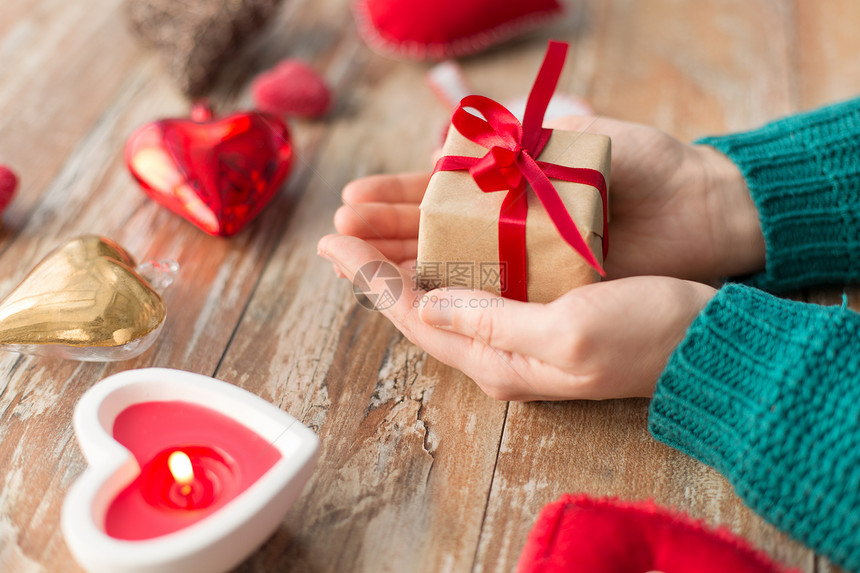 诞节,情人节假日女手礼品盒与心形装饰蜡烛燃烧木制背景紧握着诞礼物的手图片