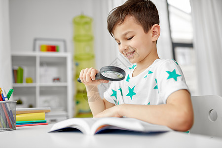 童,教育好奇心的快乐的小男孩与放大镜阅读探索书家里带放大镜家看书的男孩图片