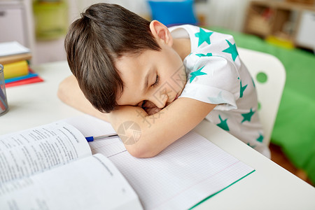 教育,童学校的疲惫的学生男孩睡家里的桌子上疲惫的学生男孩睡家里的桌子上图片