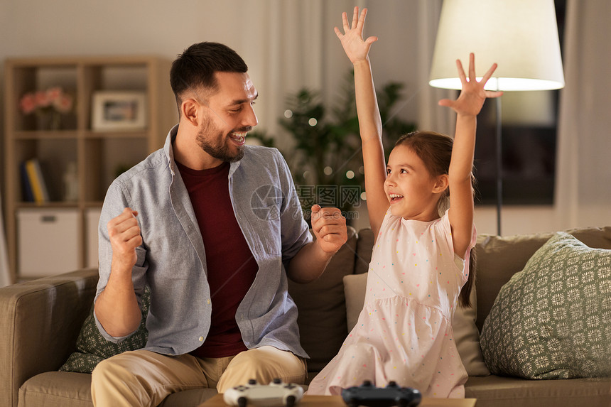 家庭,游戏娱乐活动快乐的父亲小女儿与游戏垫庆祝胜利电子游戏家里玩父亲女儿家玩电子游戏图片