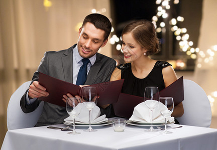 晚餐菜单约会,奢侈人们的幸福的夫妇与菜单餐厅的节日灯背景上餐厅里菜单背景
