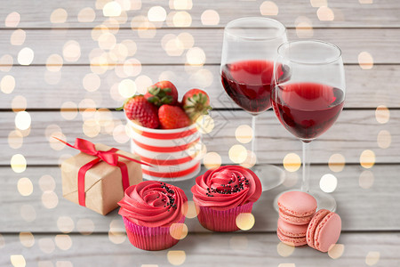 情人节糖果糖霜纸杯蛋糕,马卡龙,草莓,红酒杯礼品盒白色背景情人节的红色糖果图片