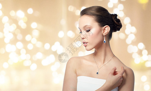 美丽,珠宝豪华美丽的亚洲妇女新娘戴着钻石耳环吊坠米色背景节日灯带耳环吊坠的漂亮亚洲女人背景图片