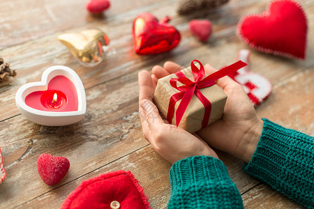 诞节,情人节假日女手礼品盒与心形装饰蜡烛燃烧木制背景紧握着诞礼物的手背景图片